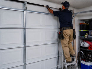 Technician installing or repairing horizontal track and hardware on a white steel sectional double garage door in Orange County, CA.