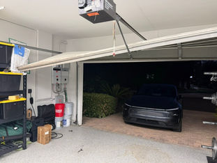Chain drive garage door opener motor mounted above white sectional double garage door during new installation in Orange County, CA.