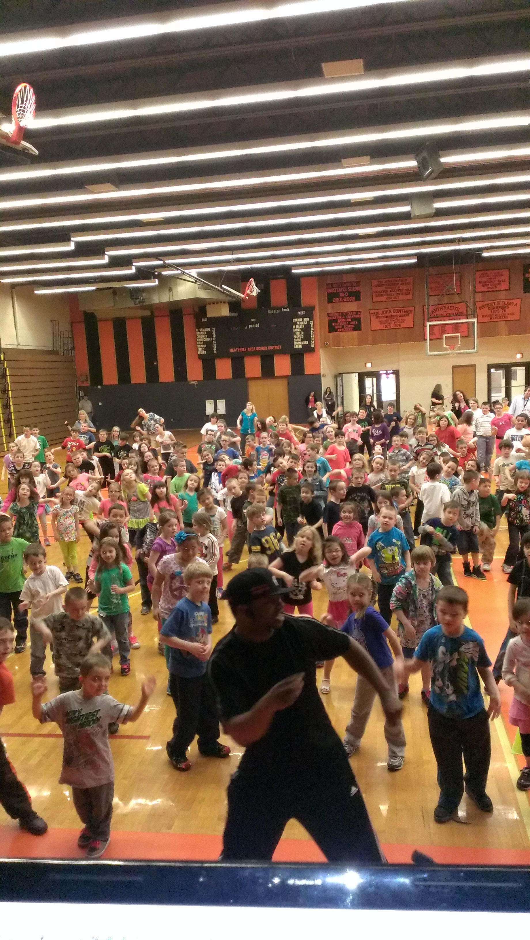 DJ Reggie leading a Respect Through Hip Hop school assembly with students participating in dance and character lessons