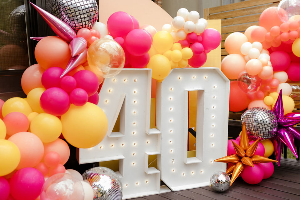 40th Birthday Balloon display with white marquee numbers surrounded by bright pink, yellow, and peach balloons