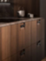 Dark wood kitchen with dramatic lighting and stone worktop