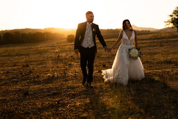 Sposi su campo al tramonto che si tengono per mano