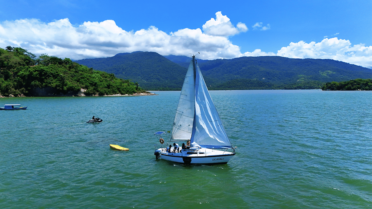Veleiro Ucayali navegando próximo às ilhas de Paraty em um dia ensolarado, com montanhas ao fundo.