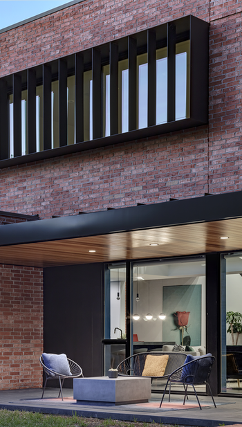 Vertical sunshades on upper level with patio and sliding glass doors.
