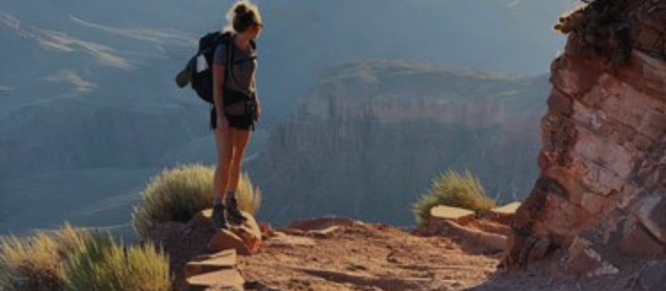 Hiker stands at edge of canyon surronded by vast mountain views - captured by the peace, perspective and mental clarity that nature offers.