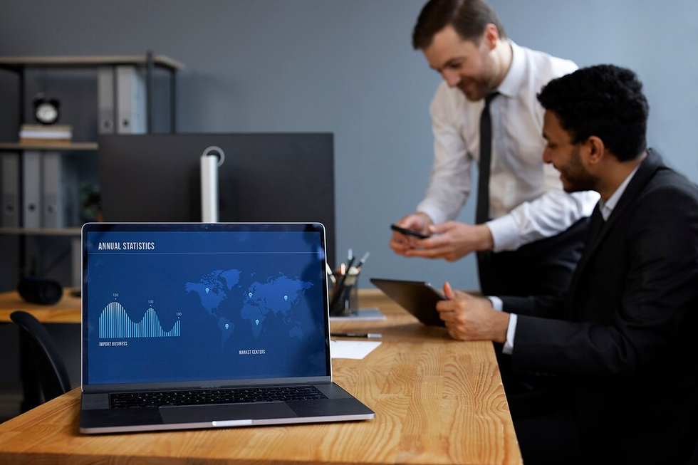 Two professionals discussing annual statistics in a modern office with a laptop displaying a world map and business charts."