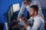 Two IT specialists collaborating in a dark monitoring room with multiple screens, showcasing expert support in Managed IT Service in Arlington Heights.