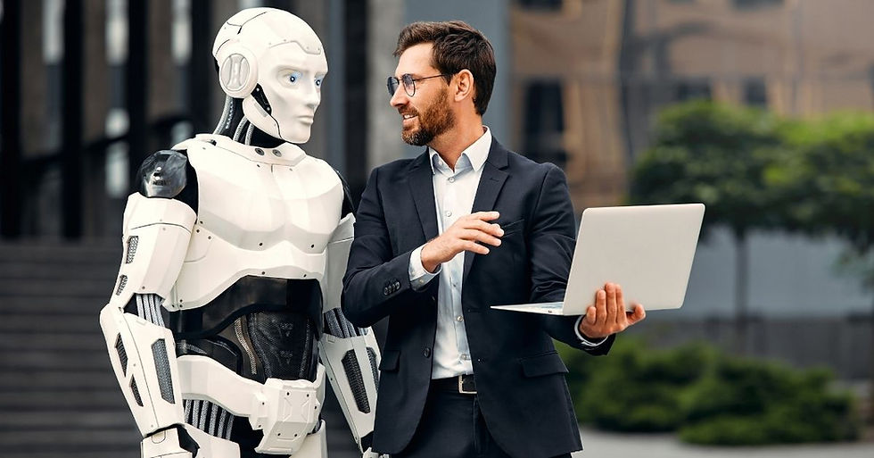 A man in a suit holds a laptop, talking to a humanoid robot. They're outdoors, with blurred buildings and greenery in the background.