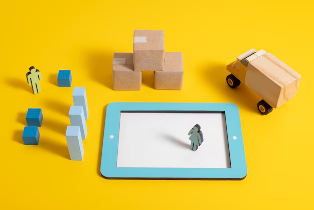 Miniature figures, boxes, and a truck arranged on a yellow backdrop with a tablet, depicting logistics. Blocks on left, tablet in center.