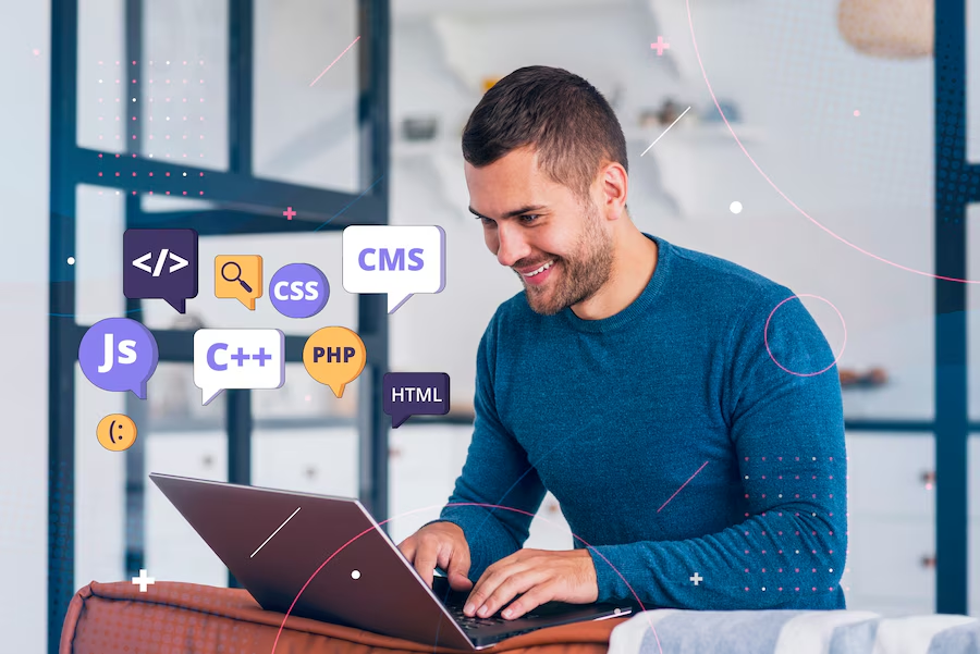 Man in blue sweater typing on a laptop, surrounded by floating tech icons like HTML, PHP, and CSS. Bright, modern room with a cheerful vibe.