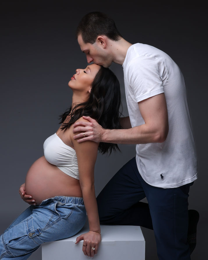 Man kisses pregnant woman's forehead