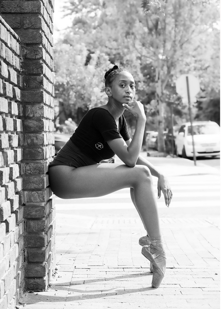 Ballet dancer en pointe leaning on a brick wall