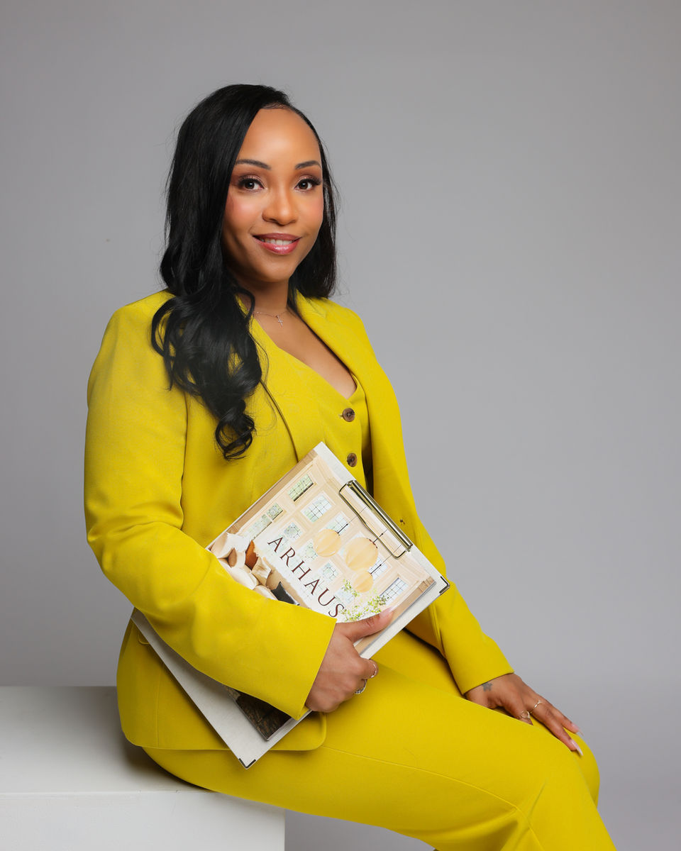 Smiling woman in yellow suit holding an ARHAUS book