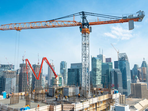 Construction workers on a high-rise job site in Toronto with cranes and skyline in the background