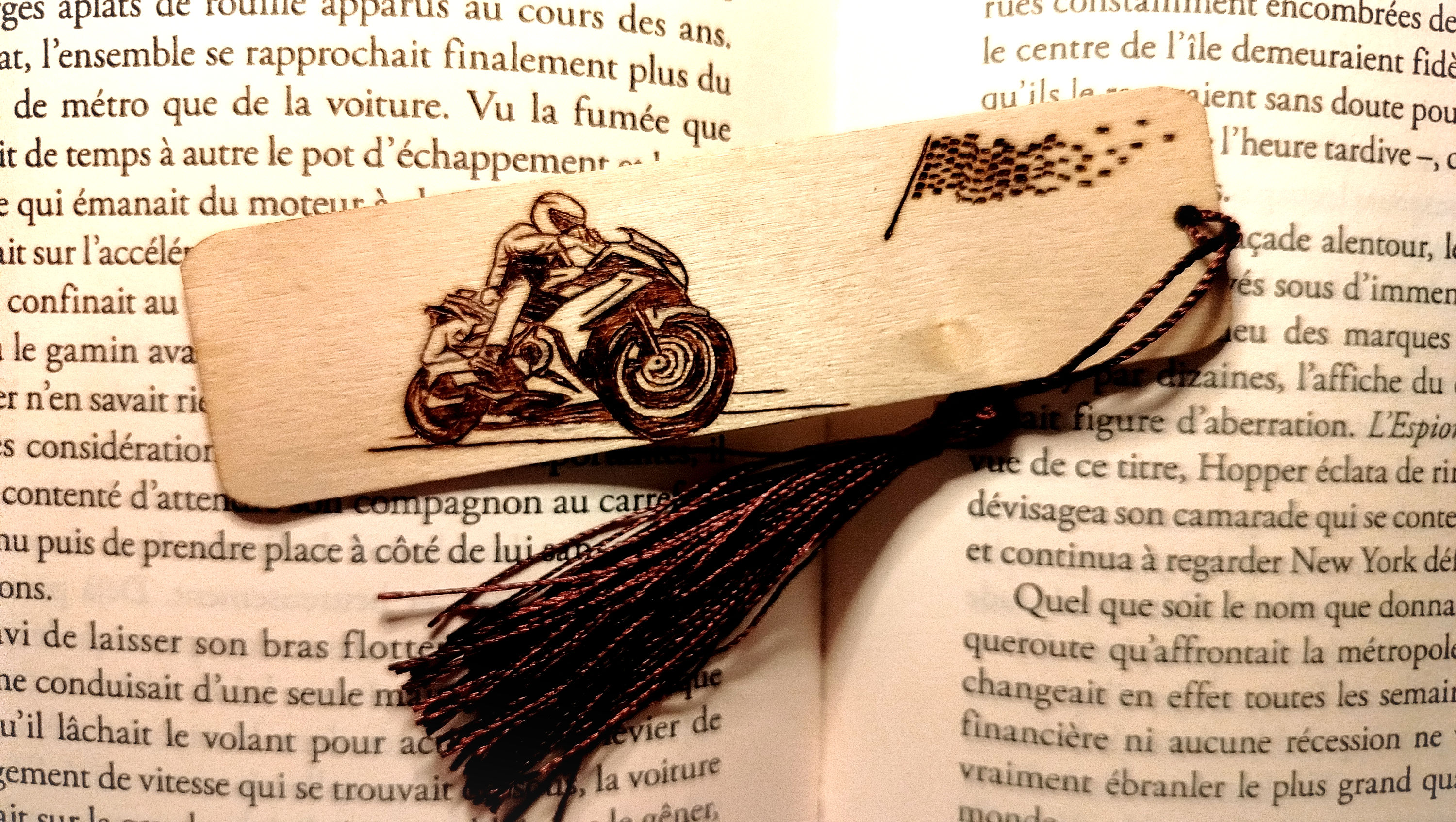 Marque page en bois gravé à la main avec une moto sportive à coté d'un drapeau à damier orné d'un pompon marron