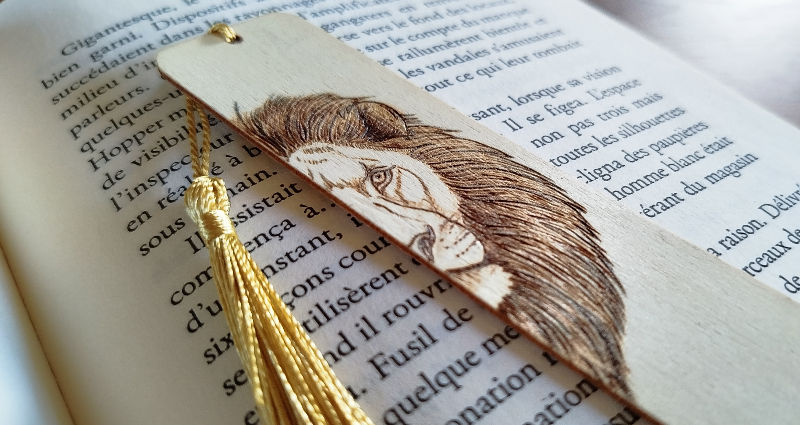 Miniature : Vue du marque page Lion gravé à la main et personnalisable. le lion est de face et coupé en deux au bord du marque page.