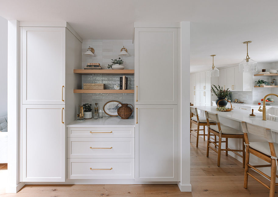 Open concept white kitchen with tall cabinetry and light oak floors flowing to the dining area
