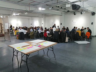 room full of people sitting around tables discussing ideas at a CIACIC workshop