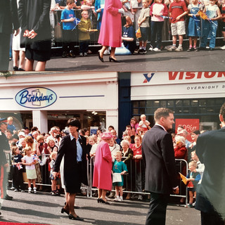 The Queen walking past a group of people behind some barriers. Stopping to chat at certain points.