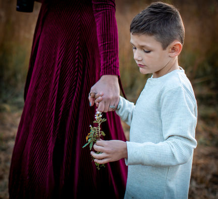 Little boy holding and looking at flower, with care that he's picked for mom.