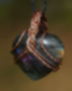 gros pendentif en labradorite en forme de coeur, serti dans du cuivre tressé, vue de face sur les reflets de la pierre