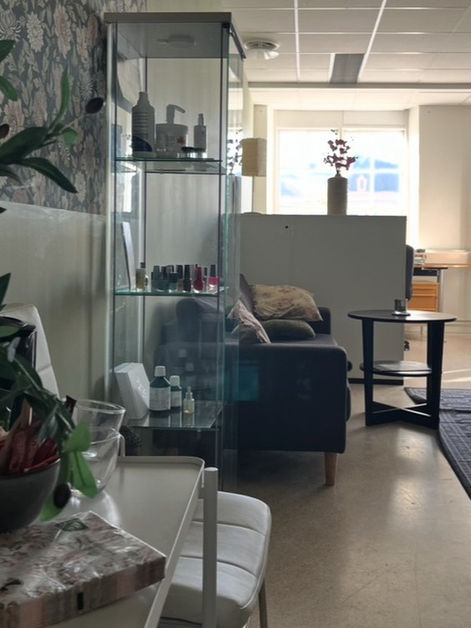 Väntrummet inne på Malins själ och fötter. En bekväm stol och ett litet bord med blommor på. En vy över resten av kliniken.