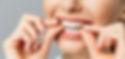 A woman is inserting her Invisalign aligners into her mouth
