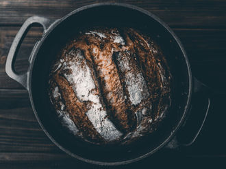 a sourdough bread in a black dutch oven on a wooden pattern