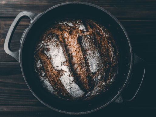 a sourdough bread in a black dutch oven on a wooden pattern