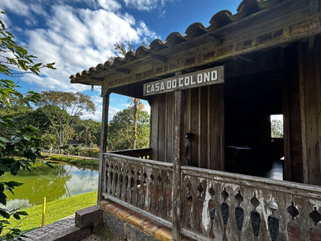 Casas de madeira históricas e moinhos no Museu ao Ar Livre Princesa Isabel, cercados por vegetação e trilhas de terra em Orleans, SC.