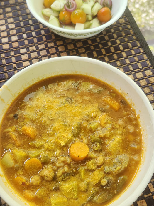 Bowl of Garden Barley & Chickpea soup served with a side cucumber, tomato, and fennel salad.