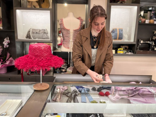 Woman browsing handmade accessories inside a hidden gem artisan shop in Cortona Italy featuring unique fashion pieces and boutique shopping in Tuscany.