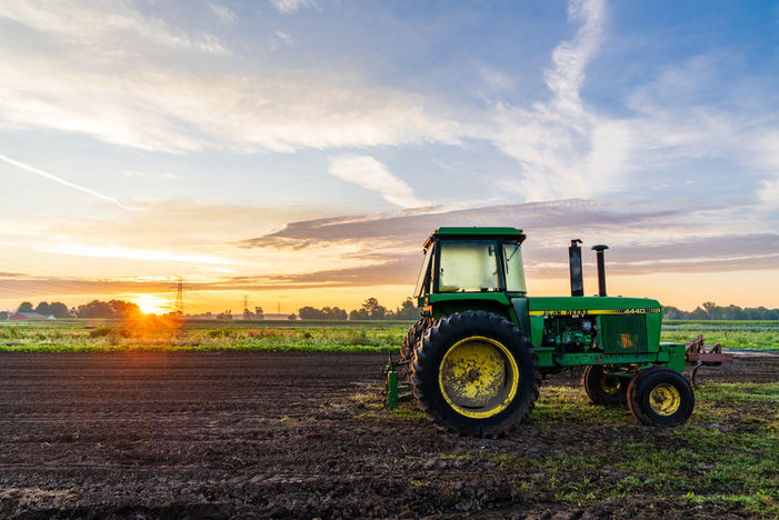 Tractor working farmland during golden hour on a Michigan farm.