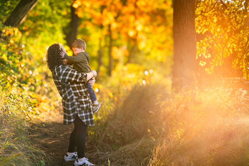 Mother holding her young child on a wooded trail during golden hour at Woollam Nature Preserve