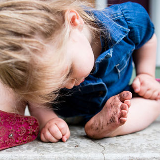 A young girl looking at her dirty feet