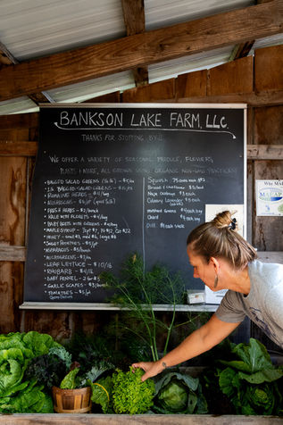 Farm stand with chalkboard sign and fresh produce on display.