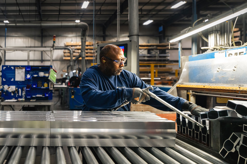 Schupan employee working with aluminum tubing on production line inside industrial facility, showcasing precision and craftsmanship in Michigan manufacturing