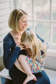 mom and daughter playfully interacting beside a window
