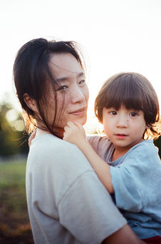 a mom and her son looking at the camera during a sunset family photography session at mcintire park in charlottesville virginia