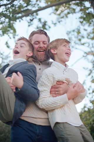 a dad playfully picking up his sons during a fun family photography session at boar's head resort in charlottesville virginia