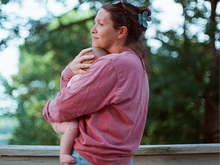 A mother holds her baby close to her chest as she smiles softly
