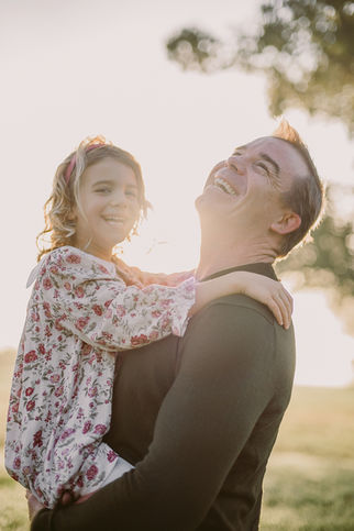 a dad laughing while holding his daughter during a sunrise family session with charlottesville film photographer Laura Richards