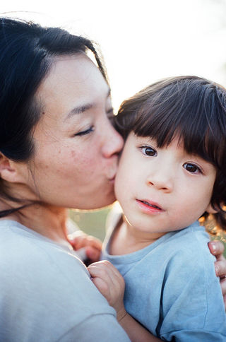 a mom kissing her son's cheek during a relaxed sunset photo session at mcintire park in charlottesville virginia