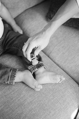 a black and white detail shot of a mom playing with toy cars on her son's feet