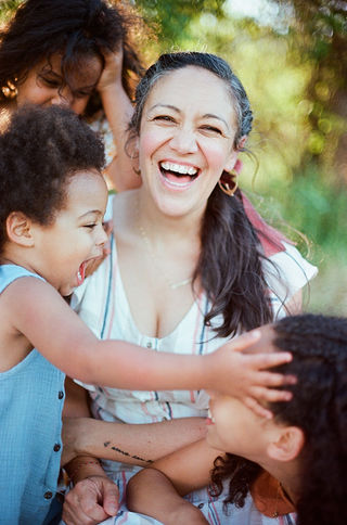 a mom surrounded by her children smiling joyfully during a golden-hour motherhood session in crozet virginia