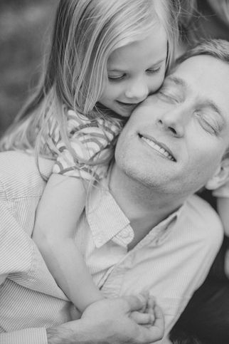 a dad soaks in a hug from his daughter during a lifestyle family photo session with charlottesville family photographer Laura Richards