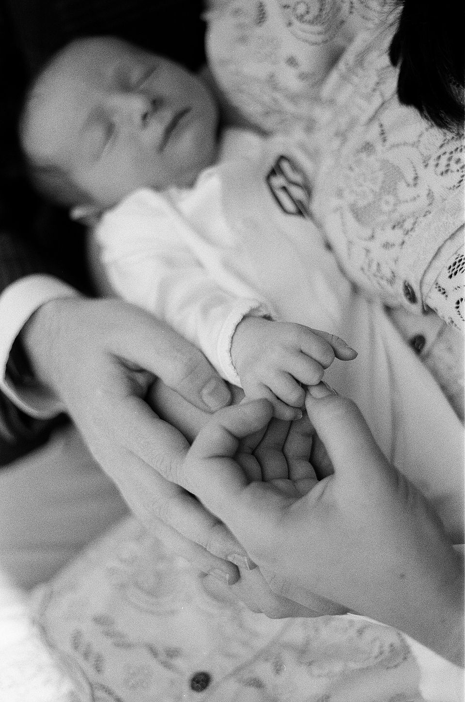 A black and white close-up of a mom touching her newborn's hand