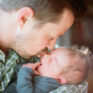 a dad kisses his newborn son