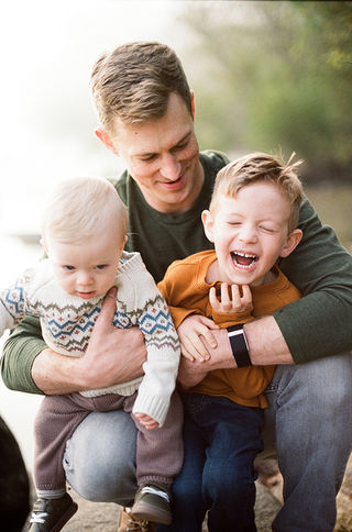 a dad playfully hugging his sons during a relaxed sunrise session at pony pasture with charlottesville family photographer Laura Richards