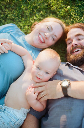 a family lying on their backs in the grass during a relaxed family photography session with charlottesville photographer Laura Richards